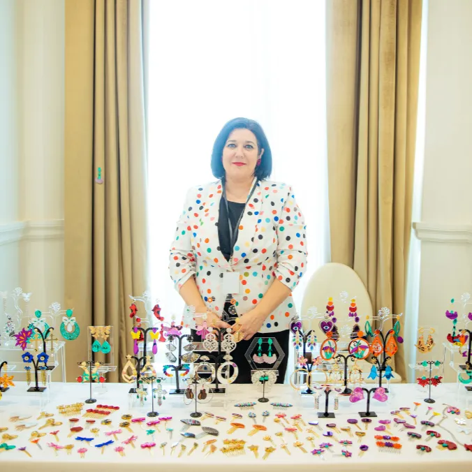 Ana Belén tras una mesa con muchas creaciones coloridas